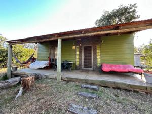 a green house with a porch with a hammock on it at Gran escape! Santa Ana in Cuchilla Alta