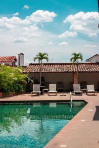 a swimming pool with lounge chairs and palm trees at Hotel Agua Escondida in Taxco de Alarc&oacute;n