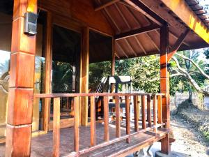 a porch of a wooden house with a bench at Muni's Lombok Bungalow in Masbagik