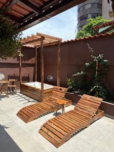 a patio with two wooden benches and a bed at Espaço Nill in Belo Horizonte