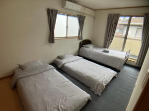 a room with three beds and a window at 4 Bedrooms, 3 Toilets, 2 bathtubs, 2 car parking , 140 Square meter big Entire house close to Makuhari messe , Disneyland, Airports and Tokyo for 18 guests in Narashino