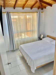 a bedroom with a white bed and a window at Apto cerca al parque de San Antonio de Pereira in Rionegro