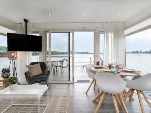 a living room with a table and chairs and a view of the water at La Serafat in Maasbommel