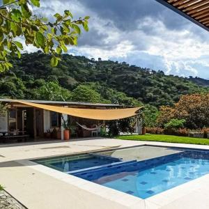een huis met een zwembad met een parasol bij Casa de campo con piscina, en un clima ideal y un paisaje excepcional in Santa Fe de Antioquia