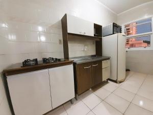 a kitchen with a white refrigerator and a sink at Central APTO Santa Cruz do Sul in Santa Cruz do Sul