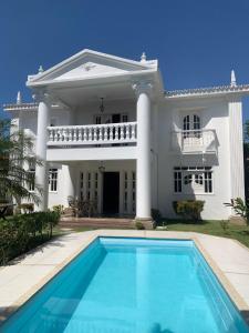 a large white house with a swimming pool in front of it at Na Casa da Santa Hostel & Bistrô - Tudo a pé - 100 mt da Passarela do Álcool in Porto Seguro
