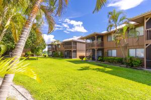 a yard in front of a building with palm trees at Bass & Sun Condominium 2/2 Bedroom in Clewiston