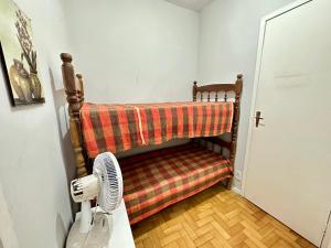 Habitación con cama con manta y ventilador. en Apartamento Américo Vespúcio, en Cabo Frío