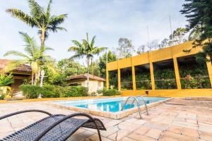 a swimming pool with two chairs in front of a building at Villa Bem Querer - Lavanda in Mairiporã
