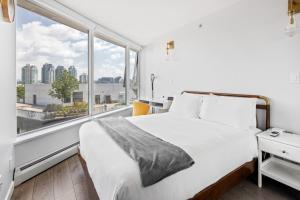 a bedroom with a white bed and a large window at GardenView Modern Condo with Parking, Gym, Pool, AC in Vancouver +14 photos