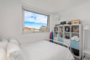 a white bedroom with a bed and a window at A Larger Slice of Fremantle 3bed apt. Wifi-Netflix in Fremantle