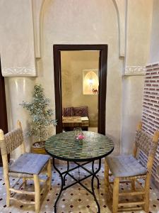 マラケシュにあるRiad Sakura Marrakechのテーブル、椅子2脚、鏡が備わる客室です。