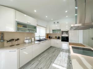 una cocina blanca con armarios y electrodomésticos blancos en Luxury Villa Heated Pool, walk to São Rafael Beach, Albufeira, en Albufeira