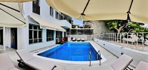 a swimming pool next to a building with chairs and an umbrella at Erato Hotel in Agia Marina Aegina