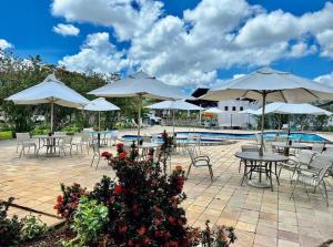 un patio con mesas y sillas con sombrillas y una piscina en Hotel Fazenda Triunfo en Areia