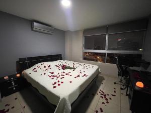 Five Stars Suites - Kennedy - Guayaquil في غواياكيل: غرفة نوم مع سرير مع زهور حمراء عليه
