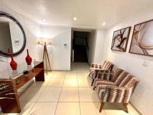 uma sala de estar com duas cadeiras e um espelho em Apartamento praia do forte em Cabo Frio