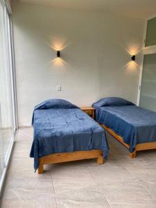 庫埃納瓦卡的住宿－Casa con Tina de Hidromasaje Climatizada，客房内的两张床,上面有蓝色的床单