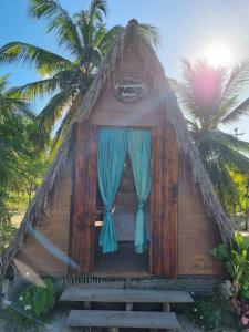 une petite cabane avec des rideaux bleus et des palmiers dans l'établissement Ecocamping Lumiar, à Amontada