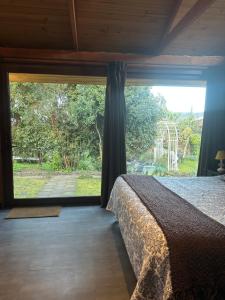 a bedroom with a bed and a large window at Hostal y Cabañas Villa Germana in Puerto Varas