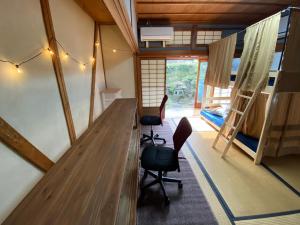 een kamer met een bureau en stoelen en een slaapkamer bij Guest House 古民家 NAGOMI in Izumi-Sano