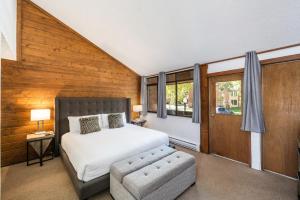 a bedroom with a bed and a chair and windows at Two Bedroom Park Ave Condo by Lespri Property Management in Park City
