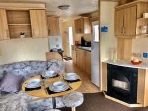 a living room with a table and a kitchen at Clacton Caravan Hire in Little Clacton