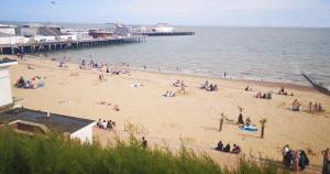 a group of people on a beach near a pier at Clacton Caravan Hire in Little Clacton