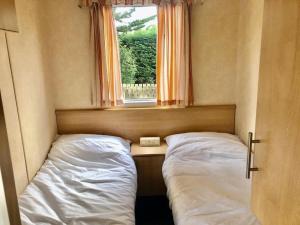 a small bedroom with two beds and a window at Clacton Caravan Hire in Little Clacton