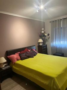 Un dormitorio con una cama amarilla con almohadas. en Apartamento com boa localização e Conforto, en Póvoa de Santa Iria