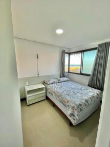 um pequeno quarto com uma cama e uma janela em Apartamento Manhattan Beach Riviera em Aquiraz