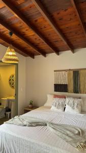 a bedroom with a white bed with a wooden ceiling at Luum Guest House in Medellín