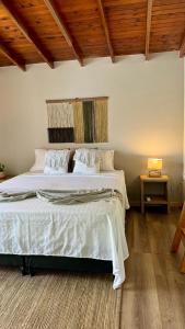 a bedroom with a bed with white sheets and a wooden ceiling at Luum Guest House in Medellín