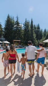 a group of people walking on the beach near a pool at Blackcomb Springs Suites by CLIQUE in Whistler