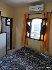 a bedroom with a bed and a window and a refrigerator at Casa agradável com piscina a 200 metros da praia in Vila Velha