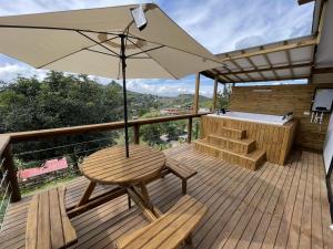 une terrasse en bois avec une table et un parasol dans l'établissement Cabañas Campestres Bosque Encantado, à Guatapé