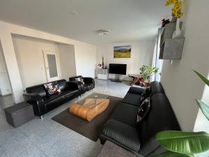a living room with black leather furniture and a television at Modernes Monteurhaus mit viel Platz in Braunschweig