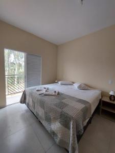 a bedroom with a large bed and a large window at Apartamento Aconchegante in Brotas
