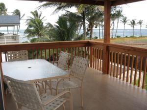 a table and chairs on a balcony with the beach at Itʻs All About the Beach in Hauula