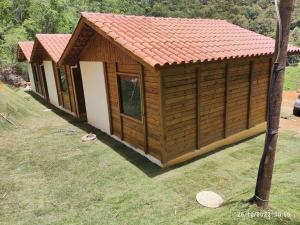 Cabaña de madera pequeña con techo rojo en Chalés Maravilha 01, en Alfredo Chaves