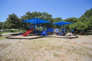 Cozy Cottage near Beaches and Downtown Sarasota في ساراسوتا: ملعب مع زحليقة ومظلات زرقاء