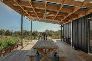 an outdoor deck with a wooden table and benches at Whimsical Willunga Getaway in Willunga