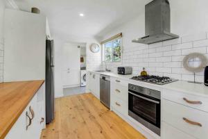 a kitchen with white cabinets and a stove top oven at Whimsical Willunga Getaway in Willunga