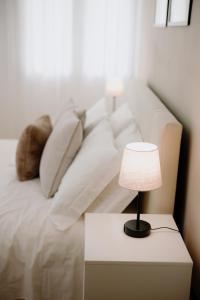 un sofá blanco con almohadas y una mesa con lámpara en Alatea Apartments Valverde, en Verona