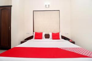 阿姆利則的住宿－寺廟景酒店，一间卧室配有一张带红色枕头的大床