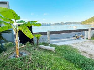 a bike parked next to a fence next to a body of water at Beach Villa Tachibana目の前が海 ペット犬OK Max7名3ユニット BBQ SUP カヤック完備 サイクリング最適 in Onomichi