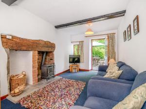 a living room with a blue couch and a fireplace at Cobbles Cottage in Talgarth