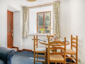 comedor con mesa, sillas y ventana en Cobbles Cottage, en Talgarth