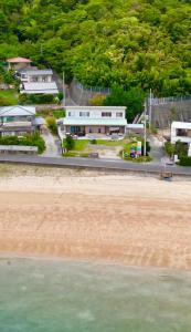 a building next to the beach and the ocean at Beach Villa Tachibana目の前が海 ペット犬OK Max7名3ユニット BBQ SUP カヤック完備 サイクリング最適 in Onomichi