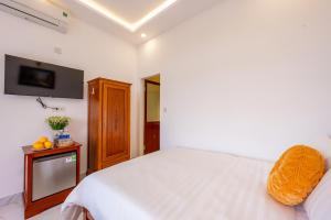 a bedroom with a white bed and a tv at Golden Sun Hotel Hoi An in Hoi An